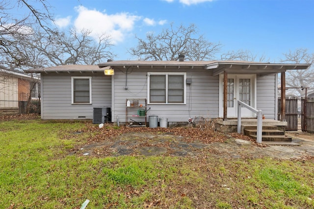 rear view of house with central AC and a lawn