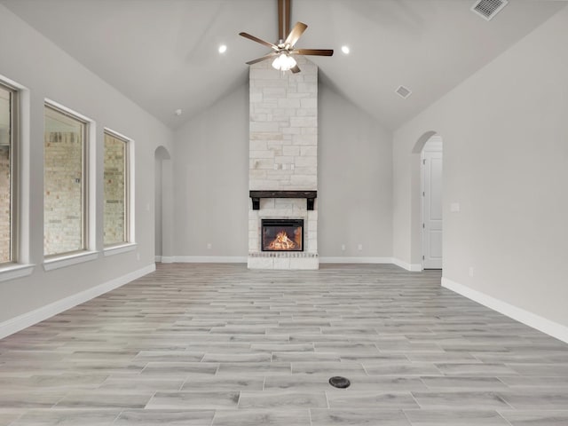 unfurnished living room with a stone fireplace, high vaulted ceiling, and ceiling fan