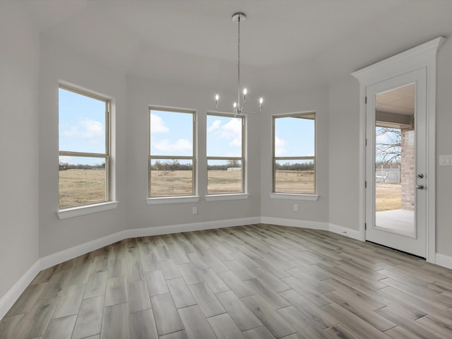 unfurnished dining area with a notable chandelier and light hardwood / wood-style flooring