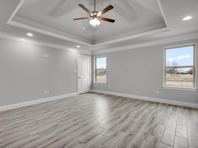 unfurnished room featuring a raised ceiling, ornamental molding, and light hardwood / wood-style floors