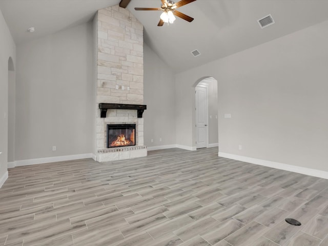 unfurnished living room featuring ceiling fan, a fireplace, beamed ceiling, and light wood-type flooring