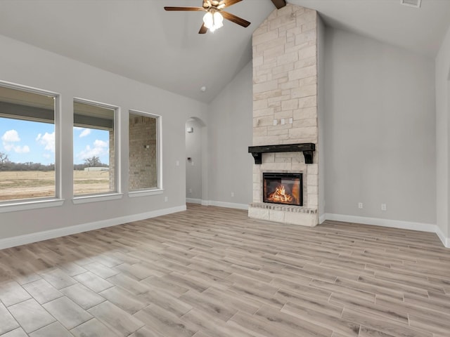 unfurnished living room featuring high vaulted ceiling, a fireplace, beam ceiling, ceiling fan, and light wood-type flooring