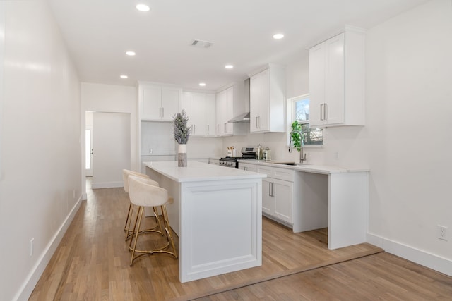 kitchen featuring white cabinetry, stainless steel range oven, light hardwood / wood-style floors, and a kitchen island