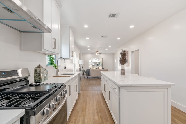 kitchen with white cabinetry, stainless steel range with gas cooktop, a center island, and exhaust hood