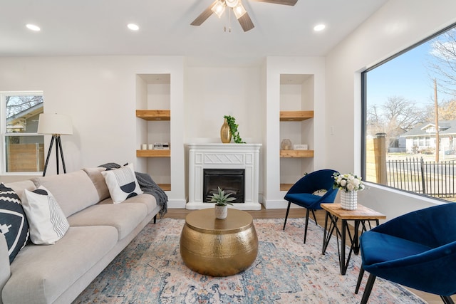 living room featuring hardwood / wood-style floors, built in features, and ceiling fan