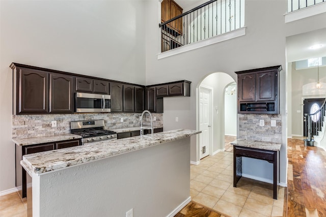 kitchen with a high ceiling, tasteful backsplash, appliances with stainless steel finishes, and light tile patterned flooring