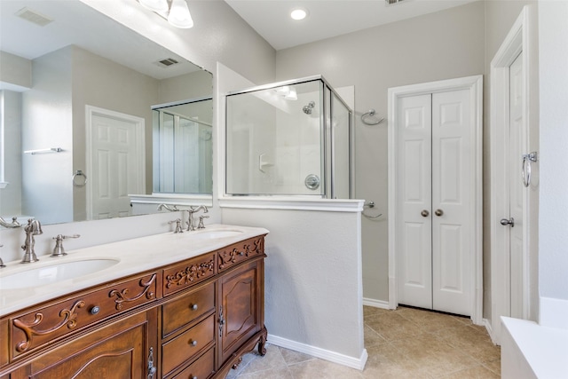 bathroom with a shower with door, vanity, and tile patterned flooring