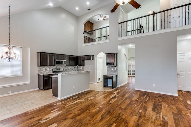 interior space with backsplash, appliances with stainless steel finishes, dark brown cabinets, and a high ceiling