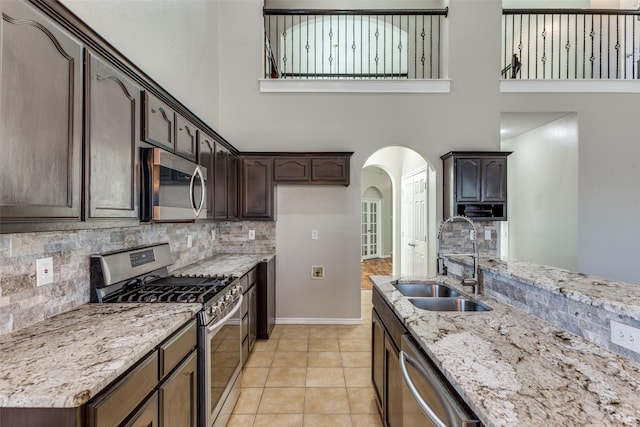 kitchen featuring sink, light tile patterned floors, a high ceiling, and appliances with stainless steel finishes