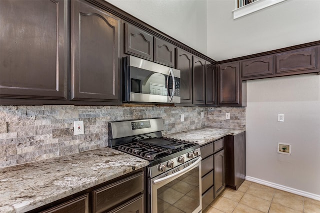 kitchen with light stone counters, dark brown cabinetry, stainless steel appliances, and light tile patterned flooring