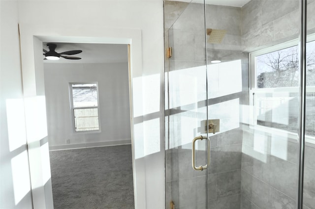 bathroom with ceiling fan, a healthy amount of sunlight, and a shower with door