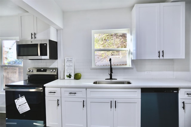 kitchen with white cabinetry, stainless steel appliances, sink, and decorative backsplash