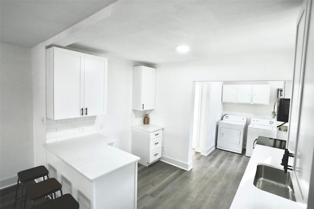 laundry area with cabinets, washer and dryer, sink, and dark hardwood / wood-style floors