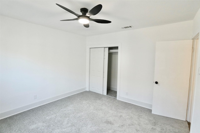 unfurnished bedroom featuring light carpet, a closet, and ceiling fan