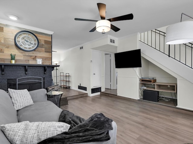 living room featuring ceiling fan, ornamental molding, a fireplace, and hardwood / wood-style floors