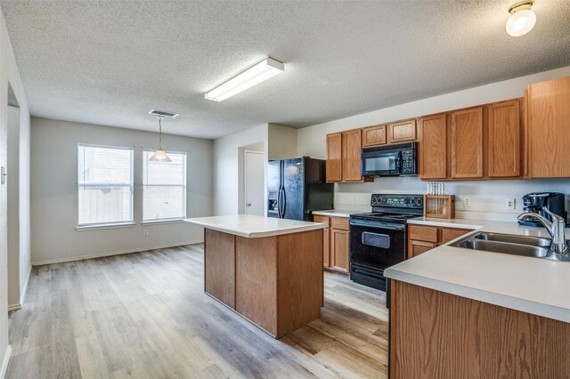 kitchen with a tile fireplace, a peninsula, light countertops, black appliances, and a sink