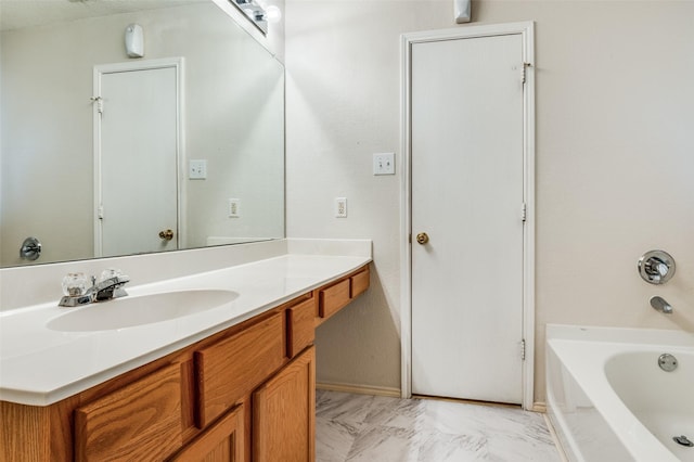 full bathroom featuring marble finish floor, vanity, baseboards, and a bathing tub