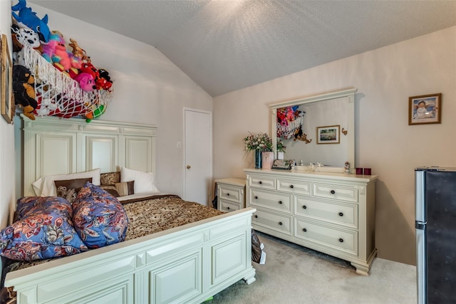 bedroom with vaulted ceiling, a textured ceiling, freestanding refrigerator, and light colored carpet