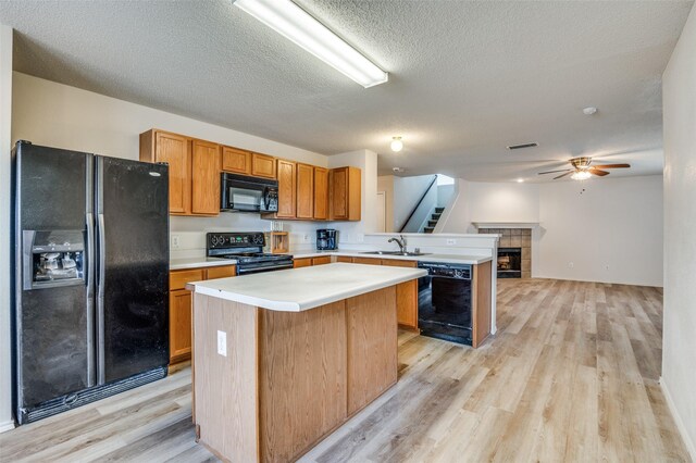 kitchen with black appliances, brown cabinets, a sink, and light countertops