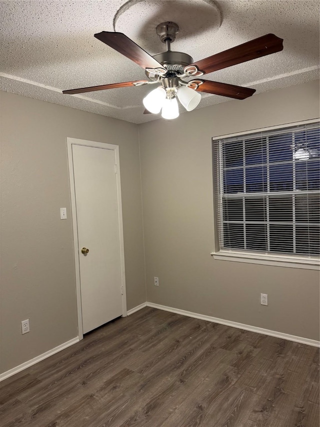 empty room with ceiling fan, dark hardwood / wood-style floors, and a textured ceiling