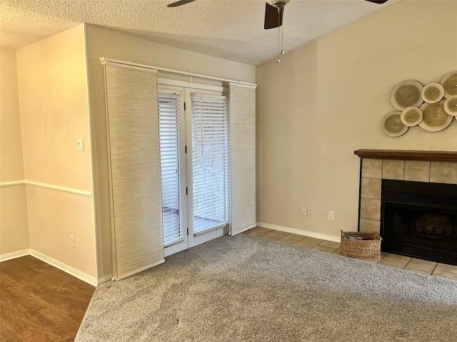 unfurnished living room featuring hardwood / wood-style flooring, a tile fireplace, a textured ceiling, and ceiling fan