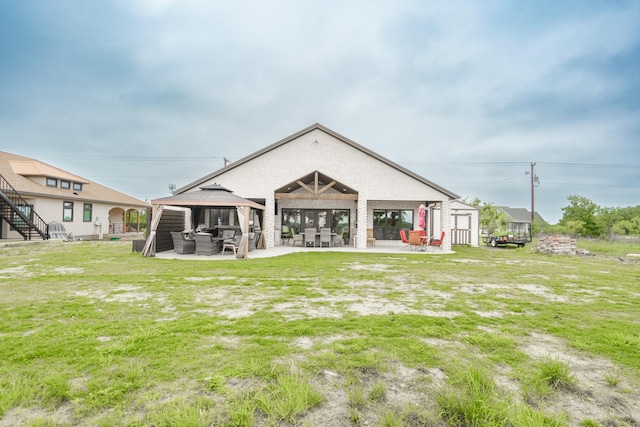 rear view of property featuring a yard, a gazebo, and a patio