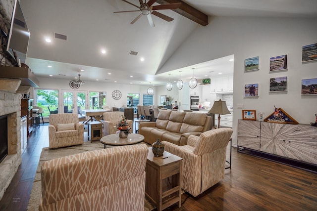 living room featuring ceiling fan, high vaulted ceiling, dark hardwood / wood-style floors, a stone fireplace, and beamed ceiling