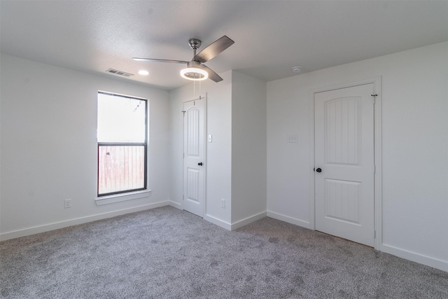 unfurnished bedroom featuring ceiling fan, light colored carpet, and a textured ceiling