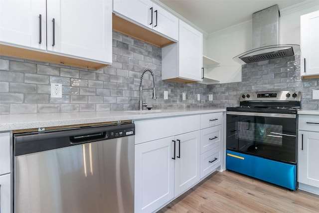 kitchen with wall chimney range hood, appliances with stainless steel finishes, tasteful backsplash, white cabinets, and light wood-type flooring