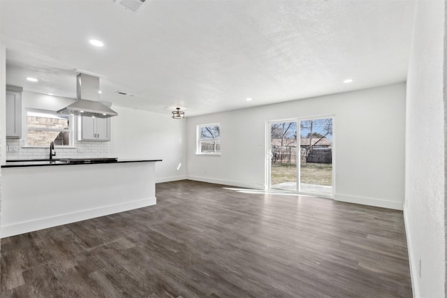 kitchen with tasteful backsplash, island exhaust hood, dark hardwood / wood-style flooring, and sink