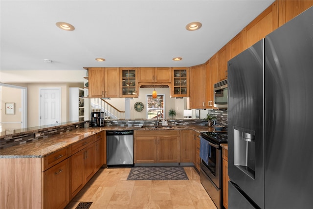 kitchen featuring appliances with stainless steel finishes, tasteful backsplash, sink, dark stone counters, and kitchen peninsula