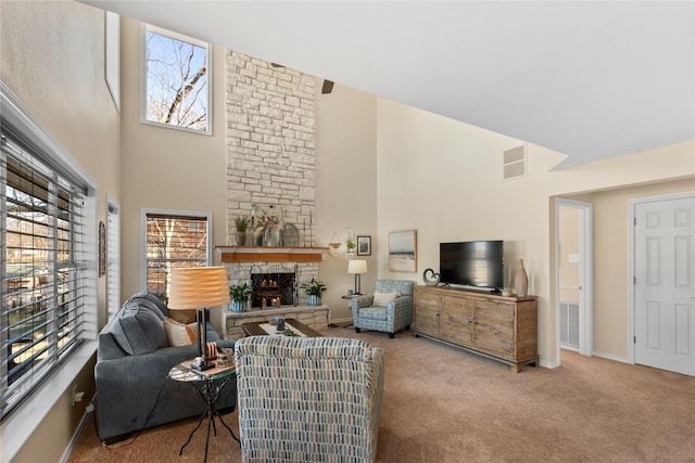 living room featuring a high ceiling, a stone fireplace, and light carpet