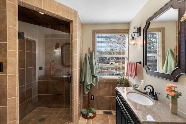 bathroom with walk in shower, vanity, tile patterned flooring, and a wealth of natural light