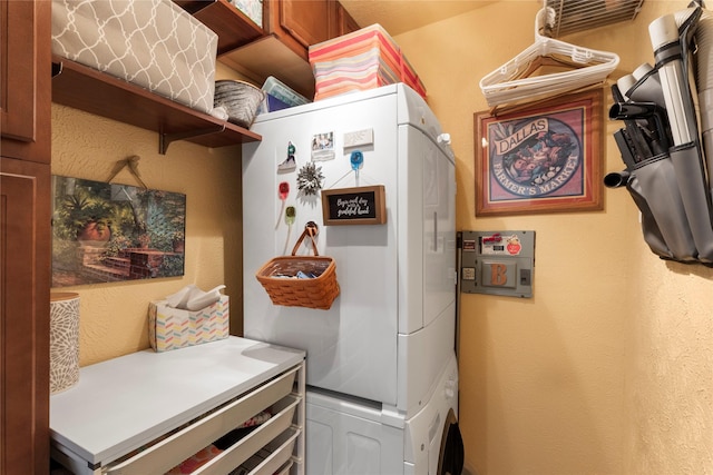 clothes washing area featuring cabinets and stacked washer / dryer