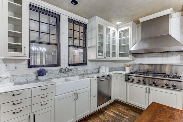 kitchen with white cabinetry, light stone countertops, sink, and wall chimney range hood