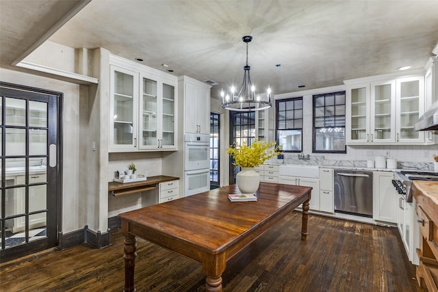 kitchen featuring white double oven, dishwasher, white cabinetry, dark hardwood / wood-style flooring, and decorative light fixtures