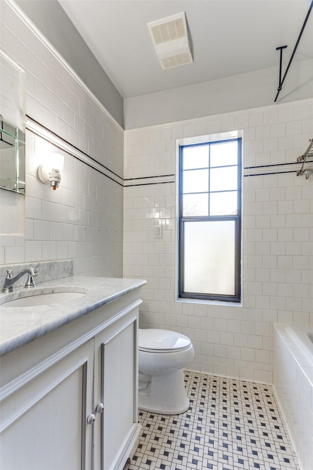 bathroom with vanity, toilet, tile patterned flooring, and tile walls