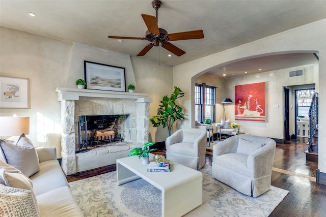 living room with a stone fireplace, hardwood / wood-style floors, and ceiling fan