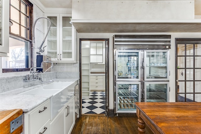 kitchen featuring stainless steel fridge, white cabinets, dark hardwood / wood-style flooring, decorative backsplash, and light stone countertops