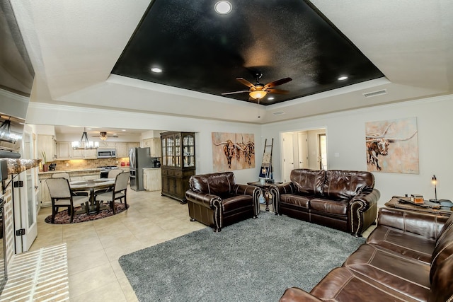 living room featuring light tile patterned flooring, ceiling fan, a tray ceiling, and crown molding