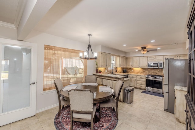 tiled dining room featuring ceiling fan with notable chandelier, ornamental molding, and sink