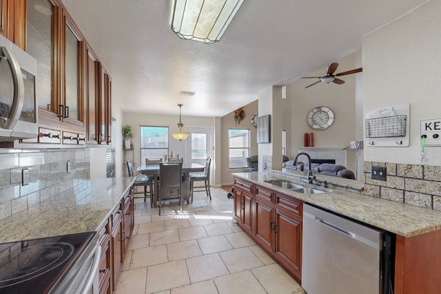 kitchen with sink, light tile patterned floors, stainless steel appliances, tasteful backsplash, and decorative light fixtures