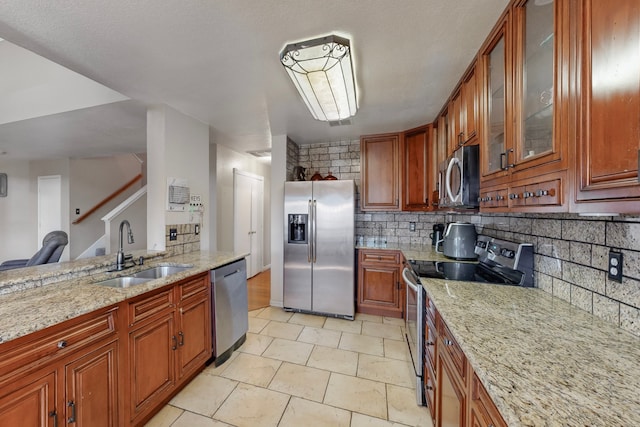 kitchen with sink, light tile patterned floors, stainless steel appliances, light stone countertops, and decorative backsplash