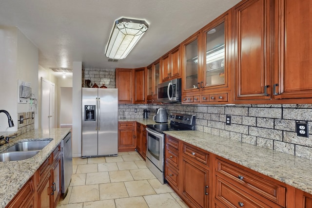 kitchen featuring stainless steel appliances, tasteful backsplash, sink, and light stone counters