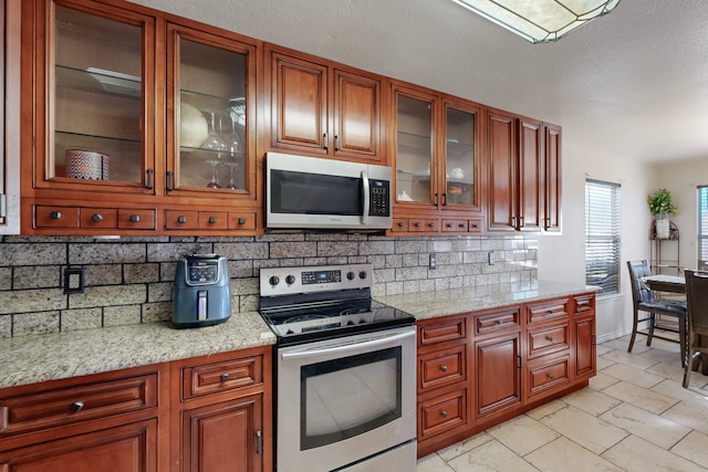 kitchen featuring stainless steel appliances, light stone countertops, and decorative backsplash