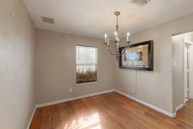 empty room with hardwood / wood-style floors and a chandelier