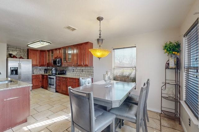 kitchen with sink, a breakfast bar area, appliances with stainless steel finishes, pendant lighting, and decorative backsplash