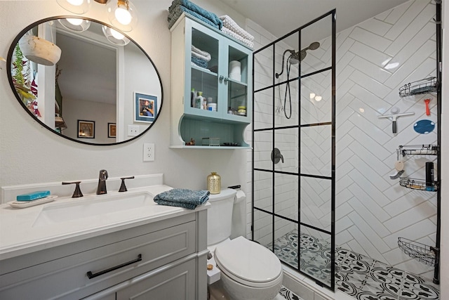 bathroom featuring vanity, toilet, and a tile shower