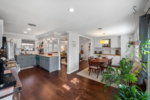 kitchen featuring appliances with stainless steel finishes, decorative light fixtures, tasteful backsplash, gray cabinetry, and dark hardwood / wood-style flooring