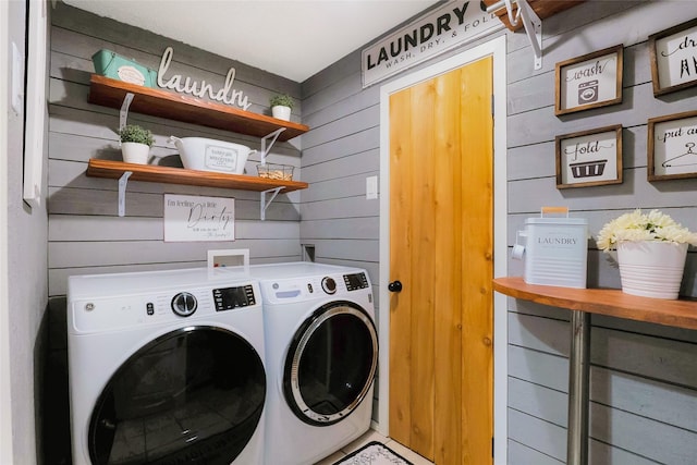 laundry area with separate washer and dryer and wood walls